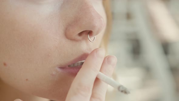 Pretty Young Woman with Vitiligo Pigmentation Sits on the Stairs and Smokes