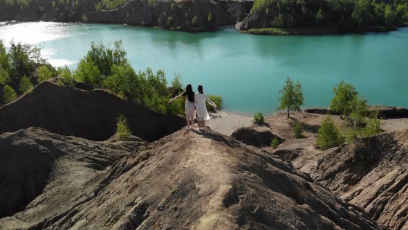 Incredible View of Two Women on Top of Mountain Against Background of Blue Lake on the Edge Hold