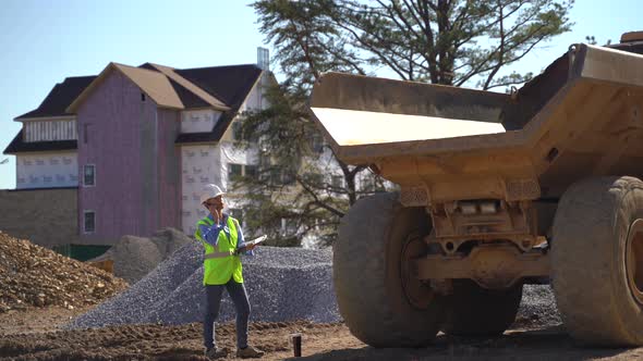 Woman engineer project manager uses a smartphone on a construction site to talk to colleagues.