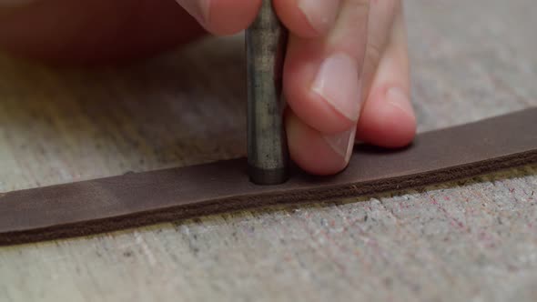 Worker Hands Applying Punch Making Holes in Leather Detail Indoors