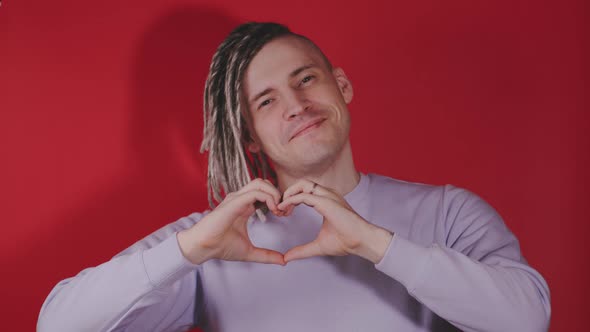 Young Handsome Man with Blonde Dreadlocks Showing Heart with Hands