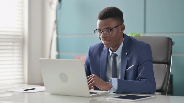 Young African Businessman Talking on Video Call on Laptop in Office