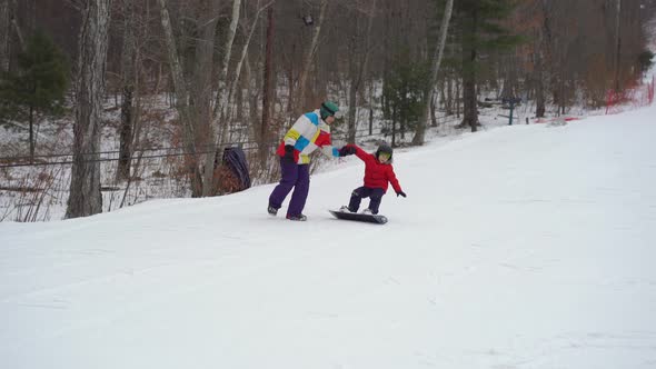 Young Man Snowboard Instructor Tiches Little Boy How To Ride a Snowboard. Winter Activities Concept