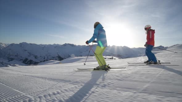 A man and woman couple skiing together in the snow at a ski resort.