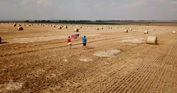 A Young Happy Couple Runs Carefree and Jumps on a Wheat Field