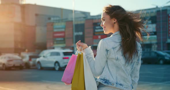 The Woman is Walking Through the Parking Lot of the Shopping Center and Smiling