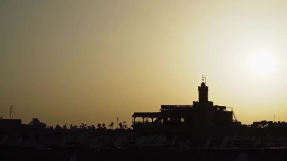 Silhouette of buildings in Moroccan desert during bright yellow sunset, slowmo
