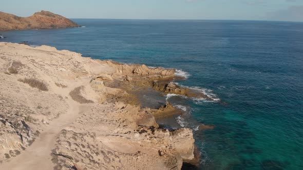 Porto dos Frades rocky coast on Porto Santo island, Madeira. Aerial forward