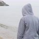 Following Shot of an Unknown Person in a Hoodie Walking Along the Seashore - VideoHive Item for Sale
