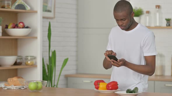Sporty African Man Taking Picture of Fruits on Smartphone in Kitchen