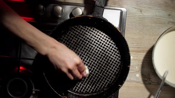 Housewife Wipes Black Frying Pan with White Fat Slice