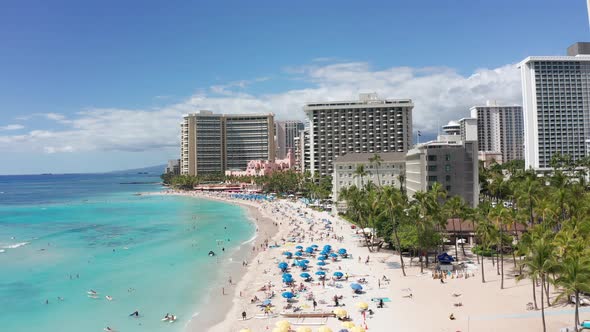 Low aerial shot flying over bustling Waikiki Beach on the island of O'ahu, Hawaii. 4K