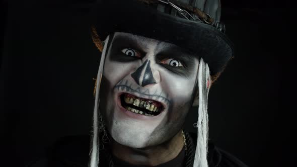 Sinister Man with Skull Makeup Appearing on Black Background, Making Faces and Ominous Smile