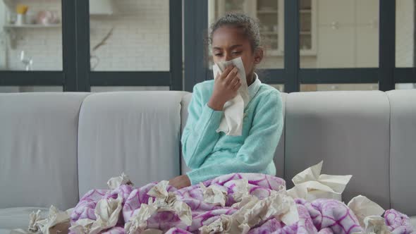 Sick Girl with Cold Blowing Nose in Tissue at Home