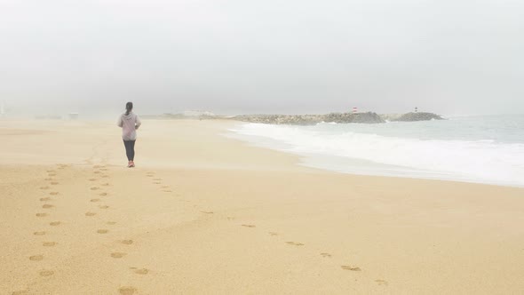 Sporty Woman Runs on Golden Beach Leaving Footprints in Sand