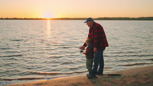 Fishing on River or Lake Shore Granddad and Grandson are Catching Fish By Fishingrod