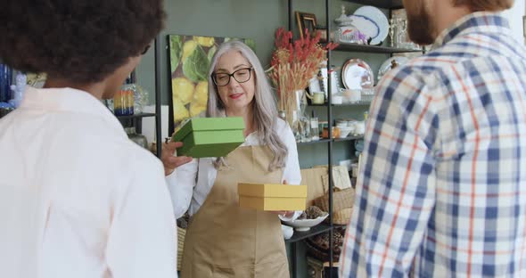 Mature Woman Giving Gift Boxes to Tourists which They Bought in Gift Shop