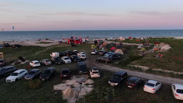 Aerial Footage of the Beach Festival with Lots of Cars and People During Sunset