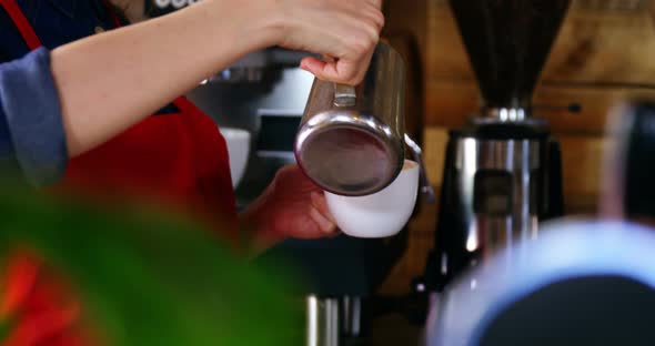 Waitress pouring milk in coffee at counter