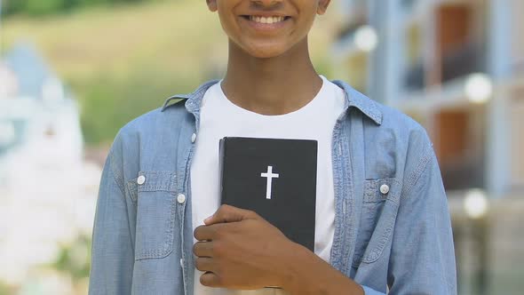 Happy Teenage Boy Holding Bible