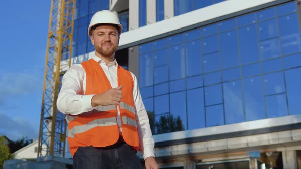 An Engineerarchitect in a White Shirt Helmet and Orange Work Vest Stands Against the Backdrop of a