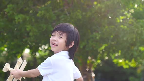 Cute Asian Child Playing Wooden Airplane In The Park Outdoors