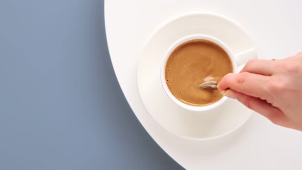 Top view of hand stirring coffee with spoon. Making morning coffee with milk