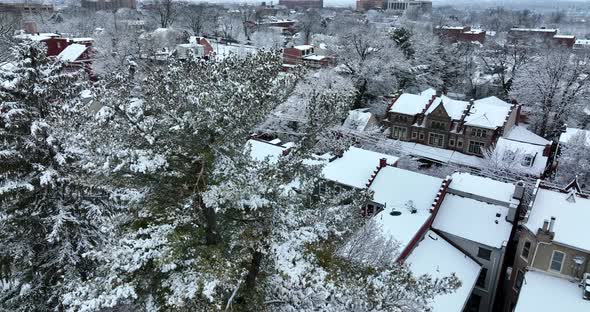 Rising aerial reveal of homes in winter snow. Evening shot of American residential homes.