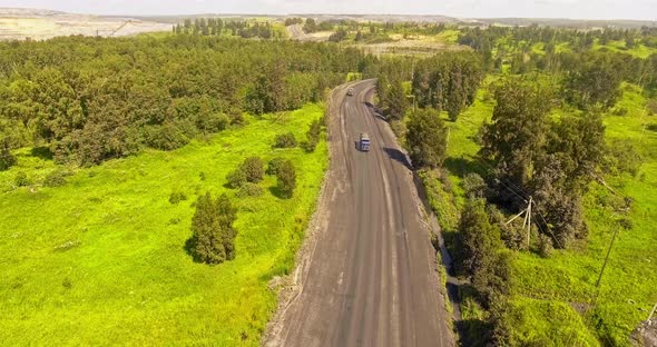 Aerial Survey of the Truck. Tilt-covered Dump Truck Carrying Coal Along the Country Road. Truck