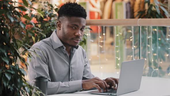 Focused Young Professional Worker Manager Typing on Laptop Working Remotely Turns to Camera Smiling