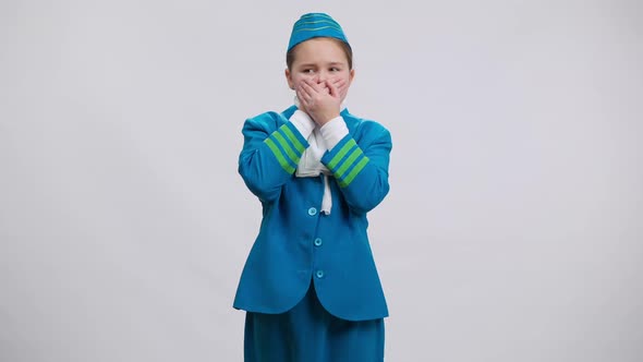 Scared Girl in Stewardess Uniform Closing Mouth with Hands Posing at White Background