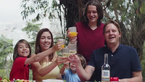 Big Caucasian Family Sitting at Table and Clinking Glasses