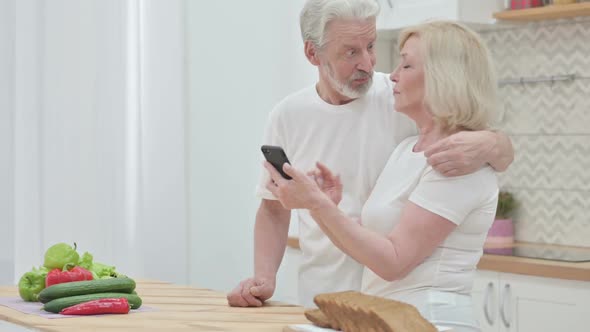 Old Couple Working on Laptop & Smartphone in Kitchen