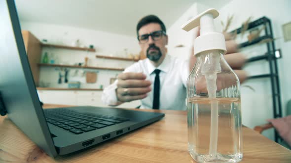 A Man Sanitizes His Hands While Working From Home. Antibacterial Sanitizer Used During Covid 19