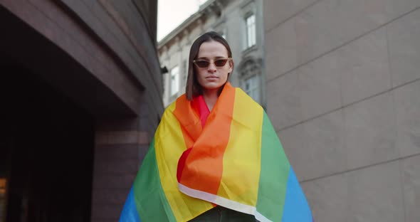 Portrait of Millennial Girl in Daylight Covering Herself in Rainbow Flag While Standing at City