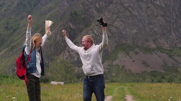 Couple in Love Travels in the Mountains with a Map and Binoculars. Friends Travelers Are Looking for