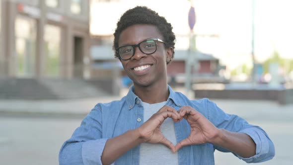 Loving Young African Man Showing Heart Shape By Hands Outdoor