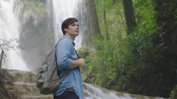 Hiker Standing In Front Of A Waterfall Deep In The Jungle