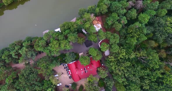 House with a red roof in the forest on the Bank of the river. Top view