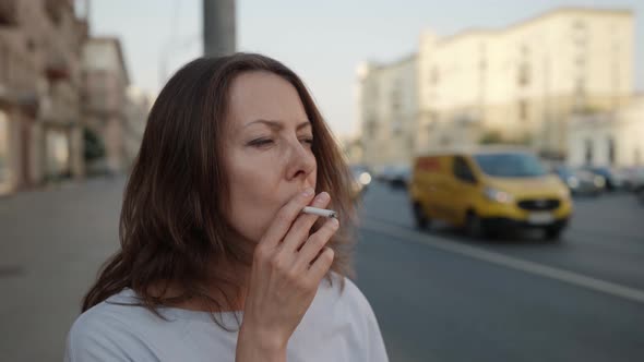 Lonely Woman is Waiting Someone on Road Junction and Smoking Cigarette