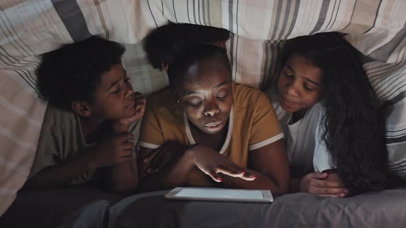 Mom Reading to Kids under Blanket