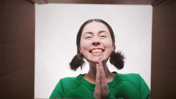 Portrait of a young happy woman opening a parcel from internet shop. Bottom view.