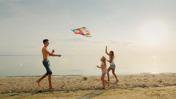 Adults and Children Play with a Kite on the Beach. Against the Backdrop of the Scenic Sky, Painted