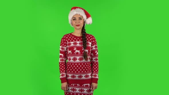 Sweety Girl in Santa Claus Hat Is Smiling Broadly and Winking. Green Screen