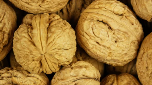 Many walnuts completely fill the frame. The movement of the camera on a large pile of walnuts. Close