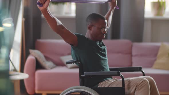 Afro-American Man on Wheelchair Training with Resistance Band