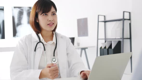 Young Asia female doctor using computer laptop talking video conference call with patient.