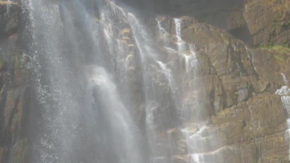 White Foaming Fresh Water Falls on Wet Brown Rocks