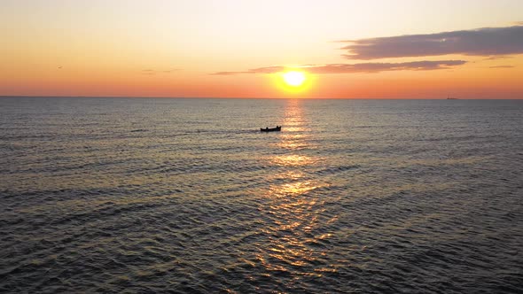 A fishing boat sailing on the sea, early in the morning, beautiful sunrise as background