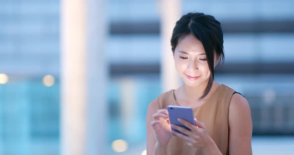 Woman look at mobile phone in city at night